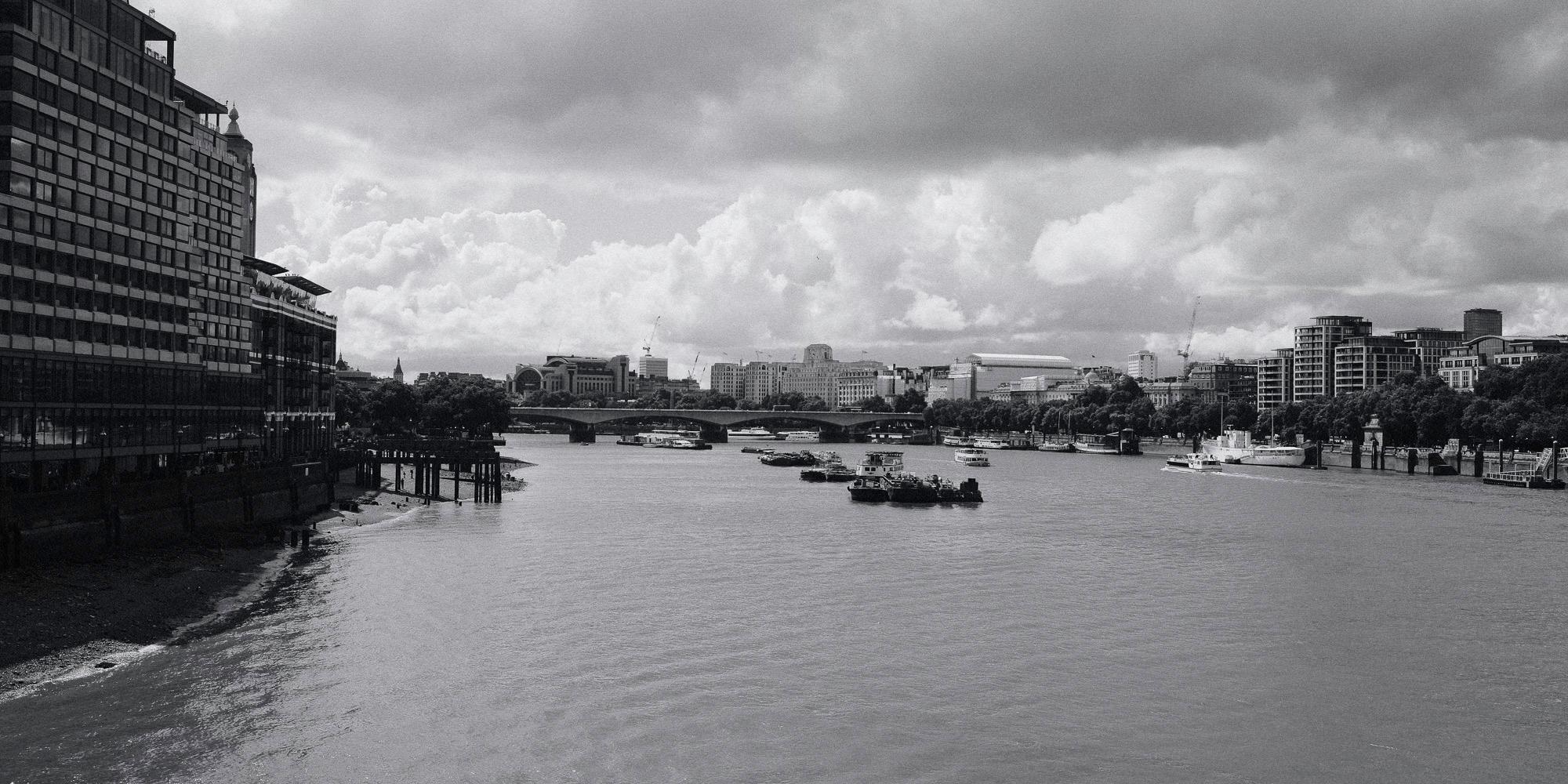 the river thames from the perspective of Blackfriars Bridge with some boats in the middle and looking onto another bridge in the background